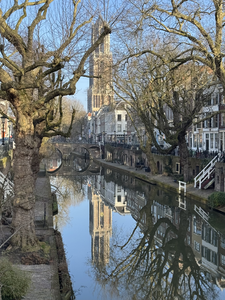 913418 Gezicht op de Oudegracht te Utrecht, vanaf de Weesbrug, met de Domtoren gespiegeld in het water.